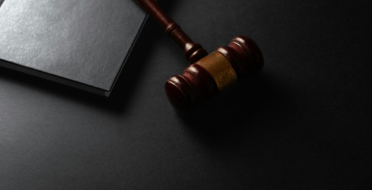 Wooden gavel resting on a dark surface next to book