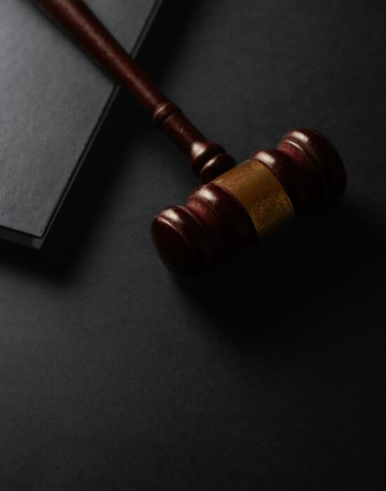Wooden gavel resting on a dark surface next to book