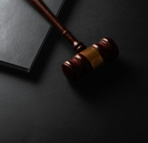 Wooden gavel resting on a dark surface next to book