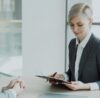 Woman in suit reviews document with man.