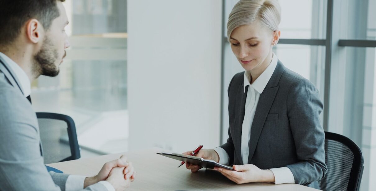 Woman in suit reviews document with man.