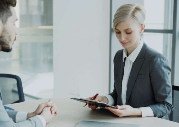 Woman in suit reviews document with man.